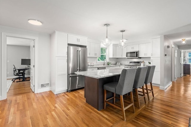 23 Redbird Rd, Wrentham, MA 02093 - kitchen featuring appliances with stainless steel finishes, white cabinetry, a breakfast bar, and a kitchen island