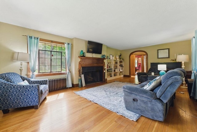 96 Craiwell Ave, West Springfield, MA 01089 - living area with radiator, arched walkways, wood-type flooring, and a fireplace with flush hearth