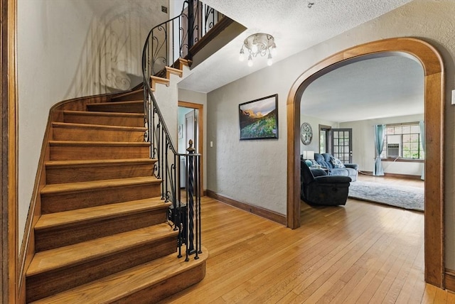 96 Craiwell Ave, West Springfield, MA 01089 - stairway with arched walkways, wood-type flooring, a textured wall, baseboards, and a textured ceiling