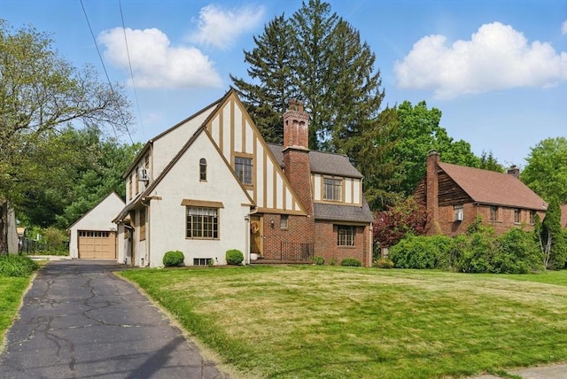 96 Craiwell Ave, West Springfield, MA 01089 - tudor-style house with a front yard, a detached garage, stucco siding, and a chimney