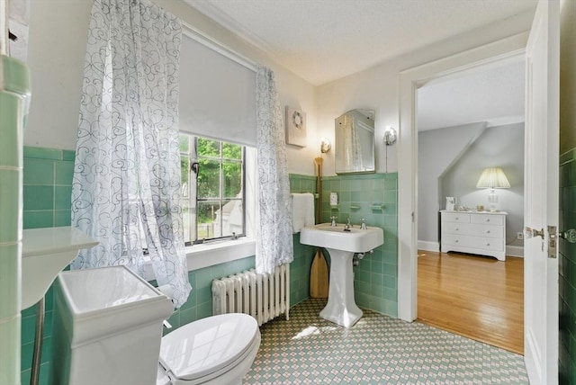 96 Craiwell Ave, West Springfield, MA 01089 - bathroom featuring radiator heating unit, tile walls, toilet, a wainscoted wall, and a sink
