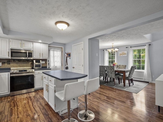 1056 Alger St, Winchendon, MA 01475 - kitchen featuring stainless steel appliances, dark countertops, a chandelier, white cabinets, and a textured ceiling