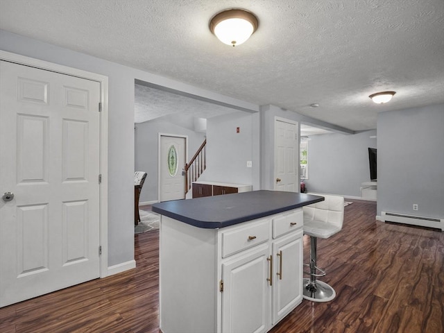 1056 Alger St, Winchendon, MA 01475 - kitchen featuring baseboard heating, a textured ceiling, dark countertops, a kitchen island, and dark wood finished floors