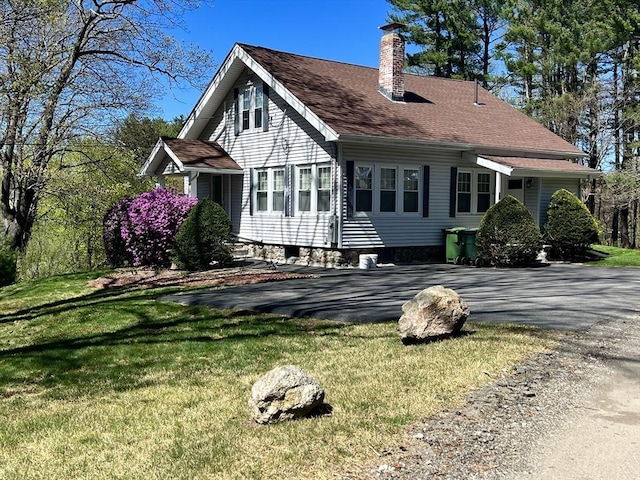 view of side of property featuring a chimney, a yard, and roof with shingles