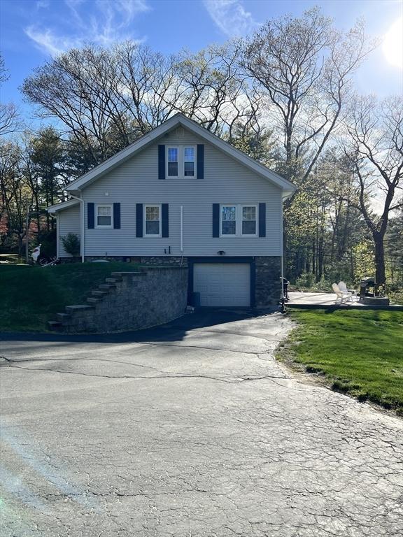 view of property exterior with driveway, a garage, and a lawn