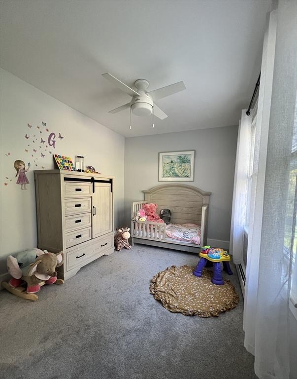 carpeted bedroom with ceiling fan and a barn door