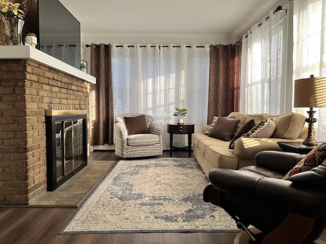 living area with crown molding, a brick fireplace, and wood finished floors