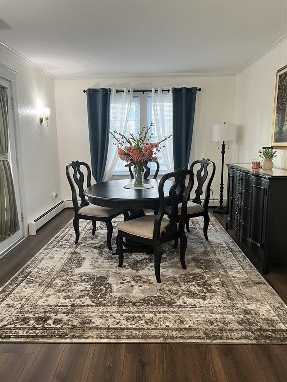 dining space with ornamental molding, baseboard heating, and dark wood-style flooring