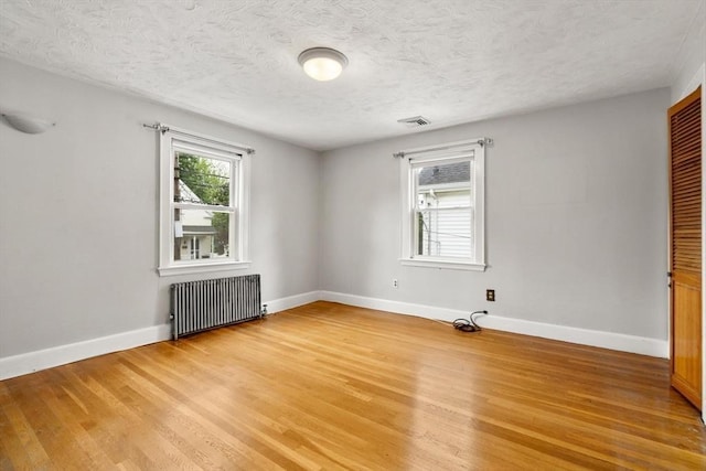 80 Joyce Kilmer Rd, Boston, MA 02132 - unfurnished room featuring radiator heating unit, light wood-style flooring, and a textured ceiling