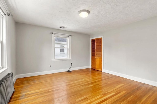 80 Joyce Kilmer Rd, Boston, MA 02132 - empty room featuring radiator, light wood finished floors, and a textured ceiling