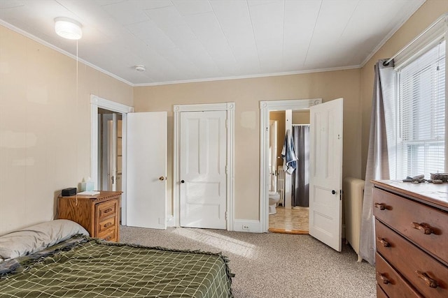 bedroom featuring connected bathroom, a closet, crown molding, and light colored carpet