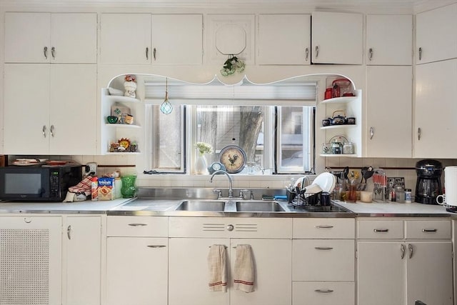 kitchen featuring sink, white cabinetry, tasteful backsplash, and stainless steel counters