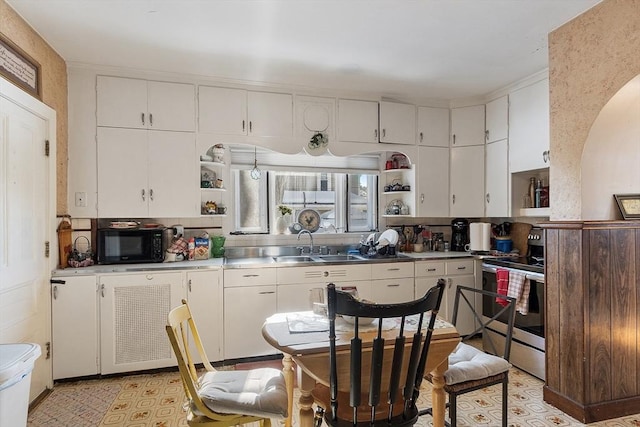 kitchen featuring sink, stainless steel range with electric stovetop, stainless steel counters, and white cabinets