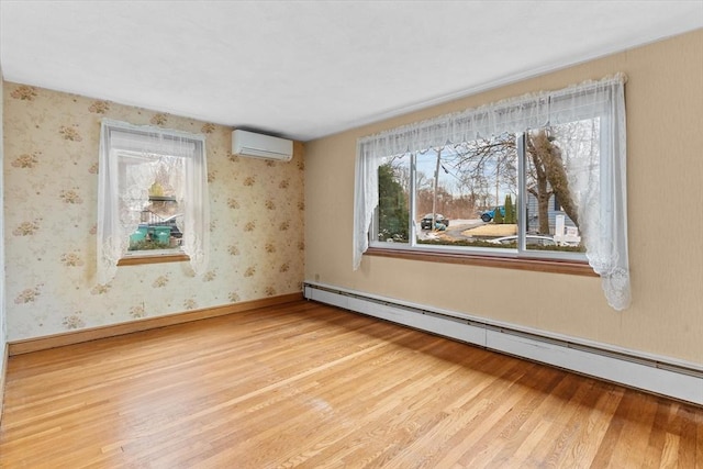 empty room featuring baseboard heating, a wall mounted AC, wood finished floors, baseboards, and wallpapered walls