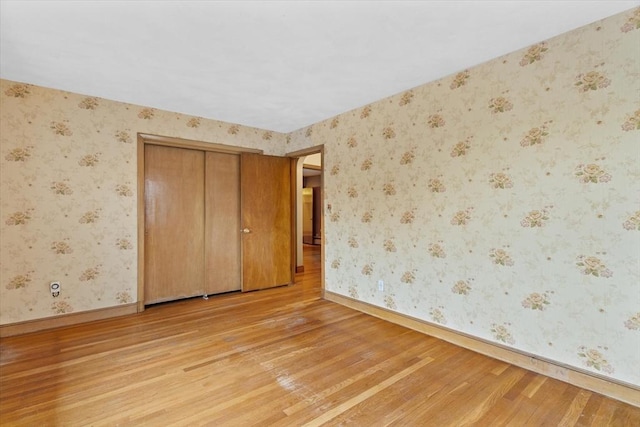 unfurnished bedroom with baseboards, light wood-style flooring, and wallpapered walls