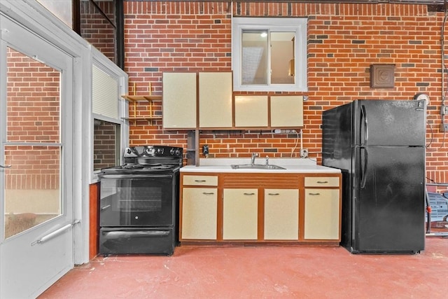 kitchen featuring black appliances, brick wall, concrete floors, and a sink