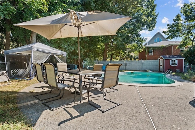 view of swimming pool featuring an outbuilding, a storage unit, a patio area, and a fenced backyard