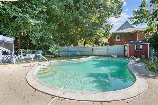 view of pool with a storage shed, a fenced backyard, and an outbuilding