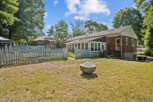 view of yard featuring entry steps, a fire pit, fence, and a sunroom