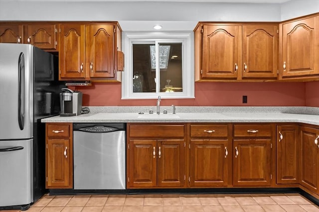 kitchen featuring light tile patterned flooring, recessed lighting, stainless steel appliances, a sink, and brown cabinets