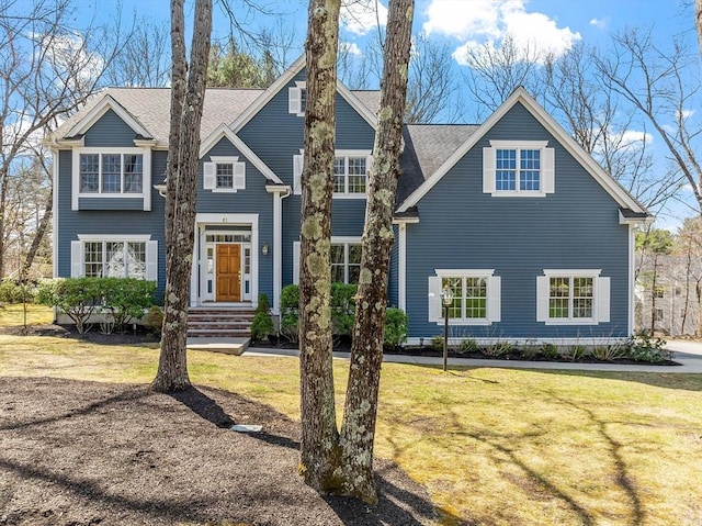 view of front facade featuring a shingled roof and a front yard
