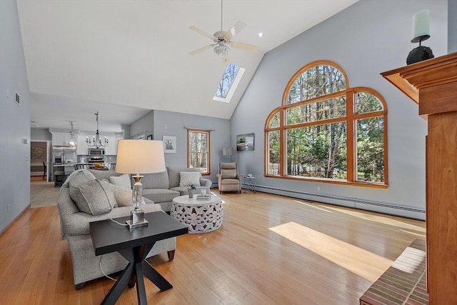 living room featuring ceiling fan with notable chandelier, wood finished floors, baseboard heating, and high vaulted ceiling