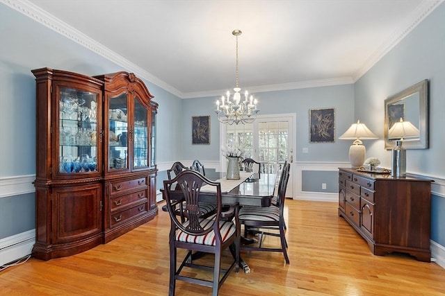 dining room featuring crown molding, a baseboard heating unit, light wood-type flooring, and a notable chandelier