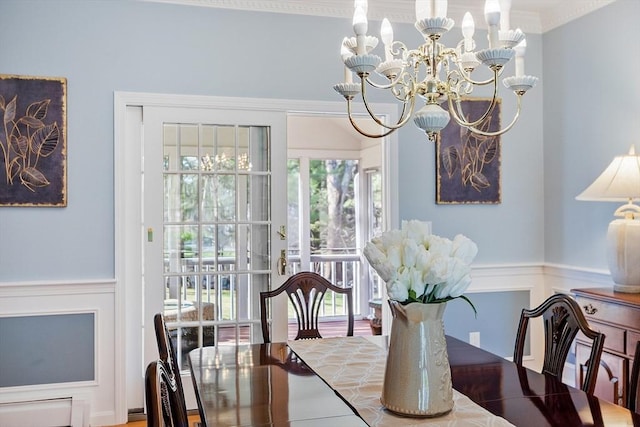 dining room with crown molding, a baseboard heating unit, a wainscoted wall, and a chandelier