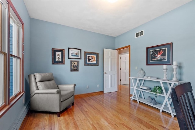 sitting room with light wood-style floors, baseboards, and visible vents