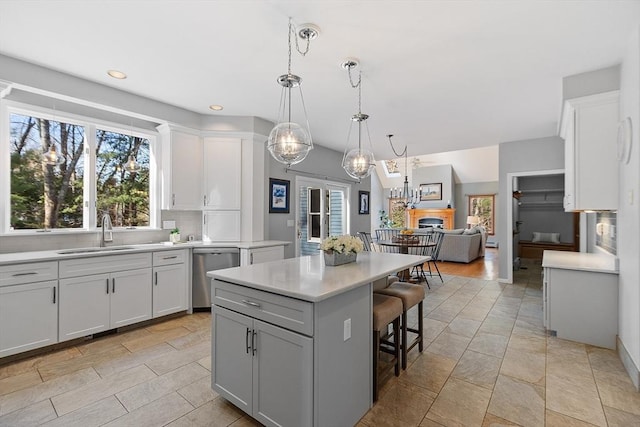 kitchen with stainless steel dishwasher, a breakfast bar, light countertops, tasteful backsplash, and a sink