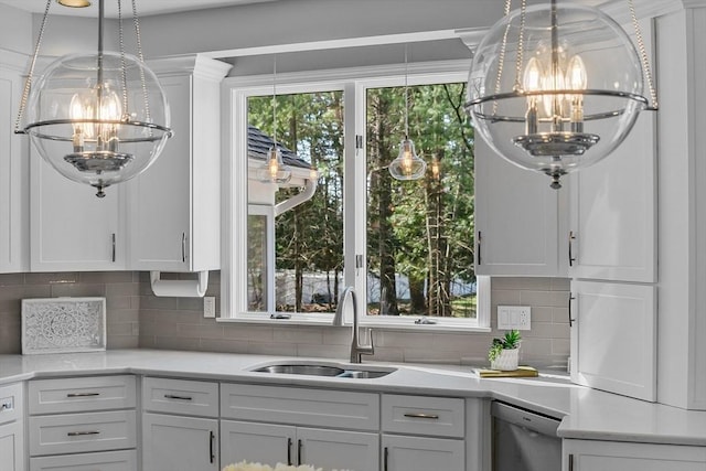 kitchen with an inviting chandelier, a sink, light countertops, white cabinetry, and stainless steel dishwasher