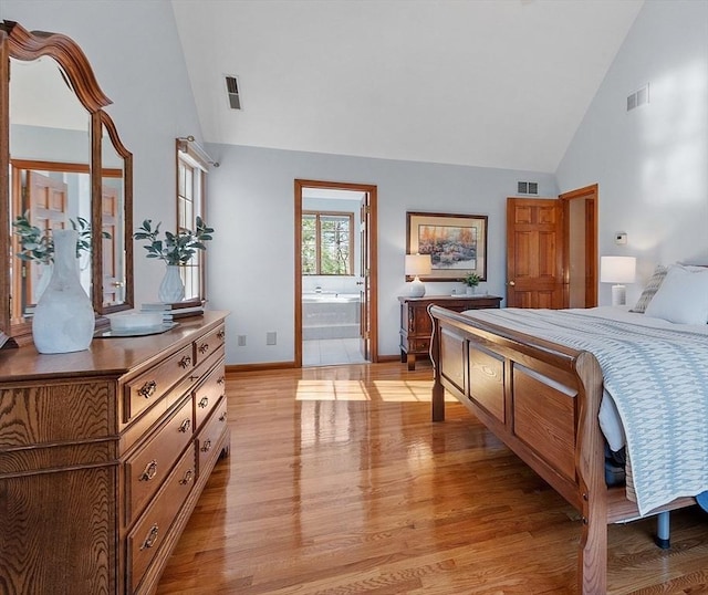 bedroom with high vaulted ceiling, light wood-style flooring, and visible vents