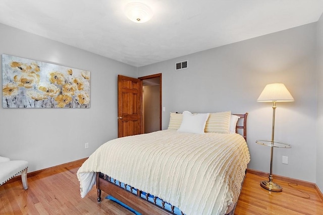bedroom featuring baseboards, wood finished floors, and visible vents