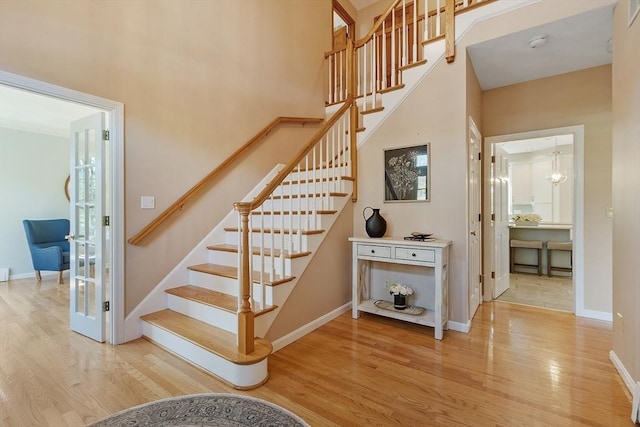 stairs with baseboards, a high ceiling, and wood finished floors