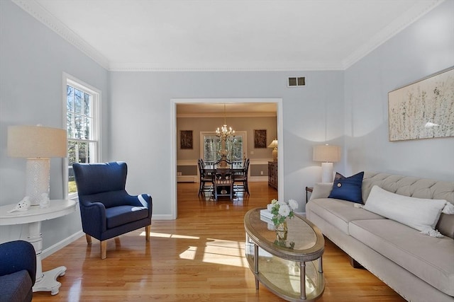 living room featuring visible vents, crown molding, baseboards, light wood finished floors, and a notable chandelier
