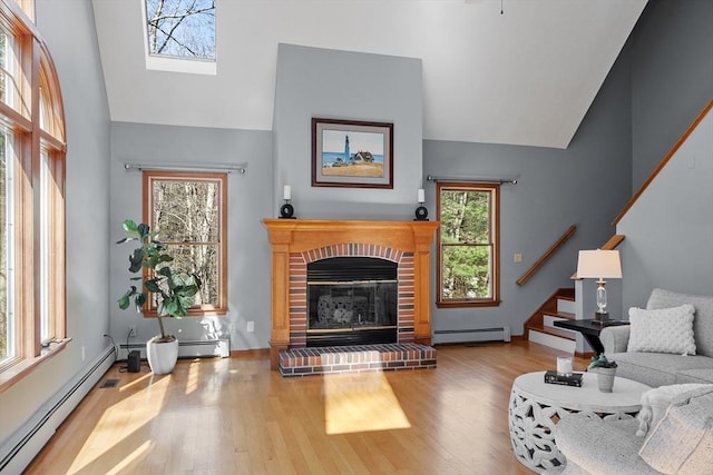 living room with stairs, high vaulted ceiling, baseboard heating, and wood finished floors