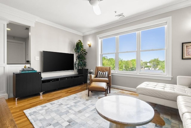 living area with ornamental molding, light wood-style flooring, and baseboards