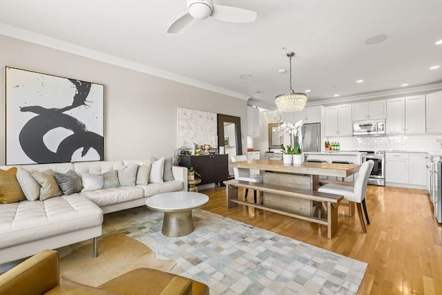 living area featuring ornamental molding, light wood-style flooring, ceiling fan, a chandelier, and recessed lighting