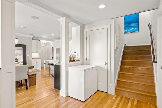 clothes washing area with light wood-style floors, recessed lighting, and ornamental molding