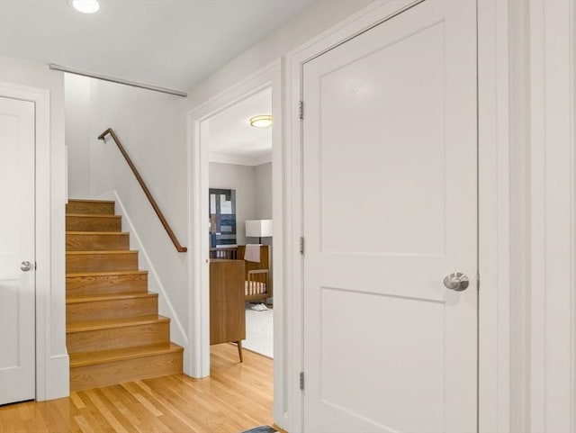 stairway with wood finished floors and ornamental molding