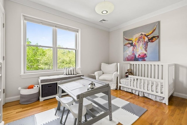 bedroom featuring multiple windows, crown molding, wood finished floors, and baseboards