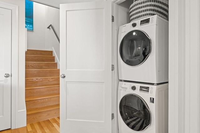 laundry room featuring stacked washing machine and dryer and light wood-style flooring