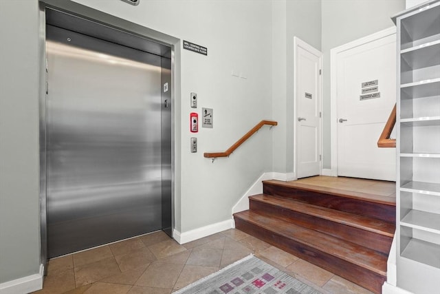 stairs featuring elevator, tile patterned floors, and baseboards