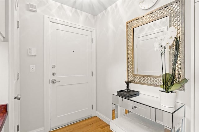doorway with light wood finished floors and baseboards