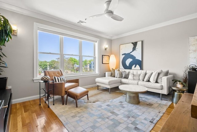 living room with a ceiling fan, baseboards, ornamental molding, and hardwood / wood-style floors