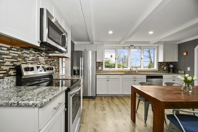 kitchen featuring tasteful backsplash, a sink, light wood-style floors, beamed ceiling, and stainless steel appliances