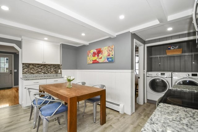 interior space with washer and dryer, a baseboard radiator, laundry area, light wood-style floors, and a wainscoted wall