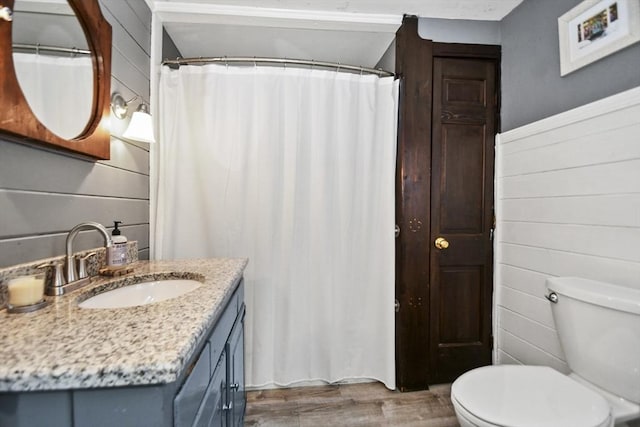 full bath with toilet, wood finished floors, and vanity