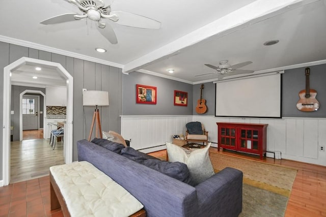 living area with a decorative wall, ornamental molding, ceiling fan, recessed lighting, and wood finished floors