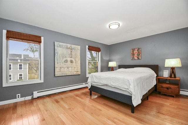 bedroom featuring baseboard heating, wood finished floors, and baseboards